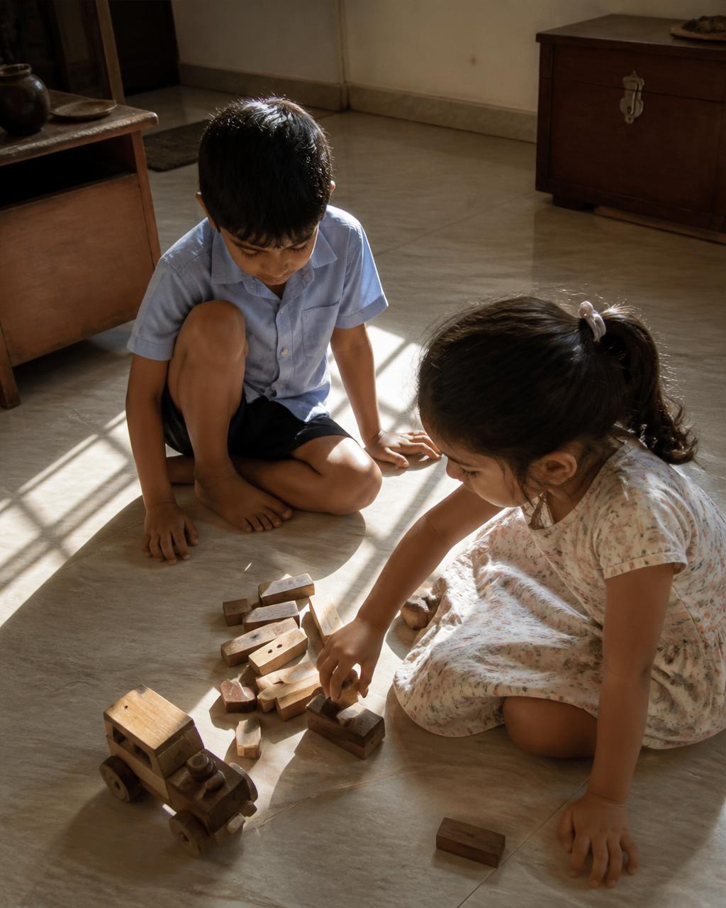 Two children playing with wooden blocks on a sunlit floor